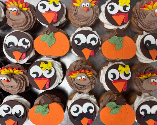 Collection of cupcakes decorated to resemble turkeys and pumpkins for a festive theme.