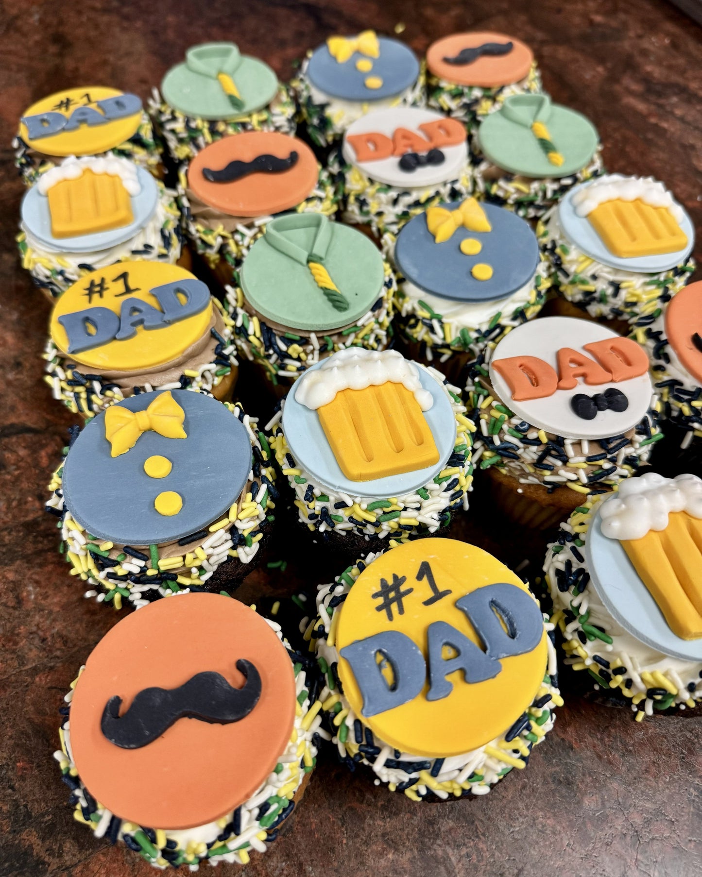 Cupcakes decorated with 'DAD' and '#1 DAD' text, along with mustache and beer mug symbols on a wooden surface.