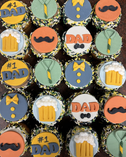 Cupcakes decorated with father-themed designs including ties, beer mugs, and mustaches on a dark background.