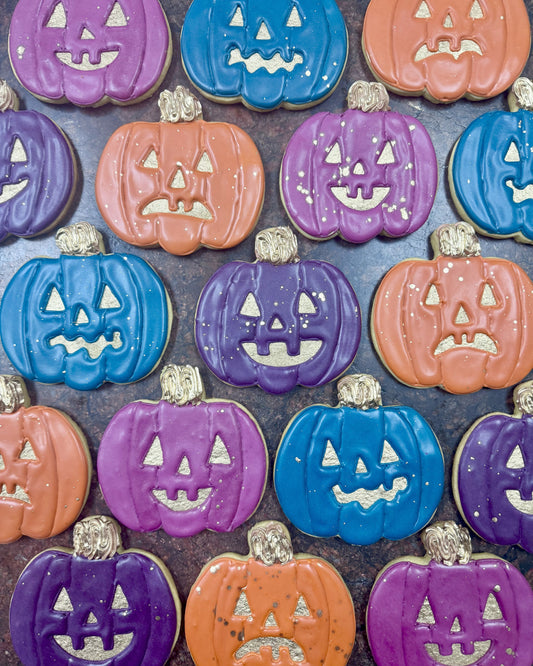 Colorful Halloween-themed cookies shaped like jack-o'-lanterns