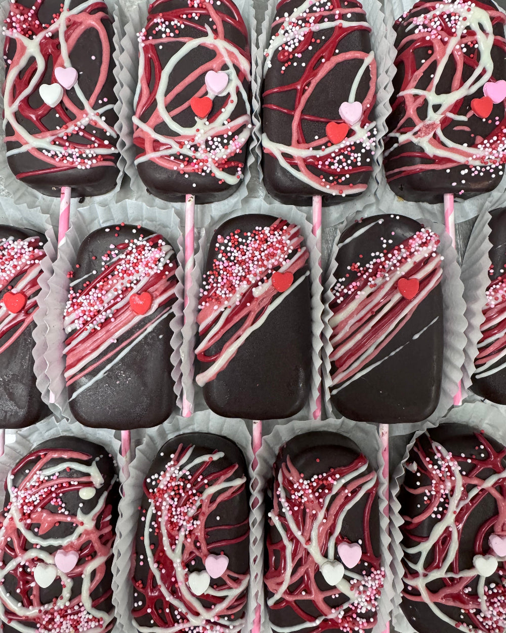 Assorted chocolate treats with pink and white drizzle in a box